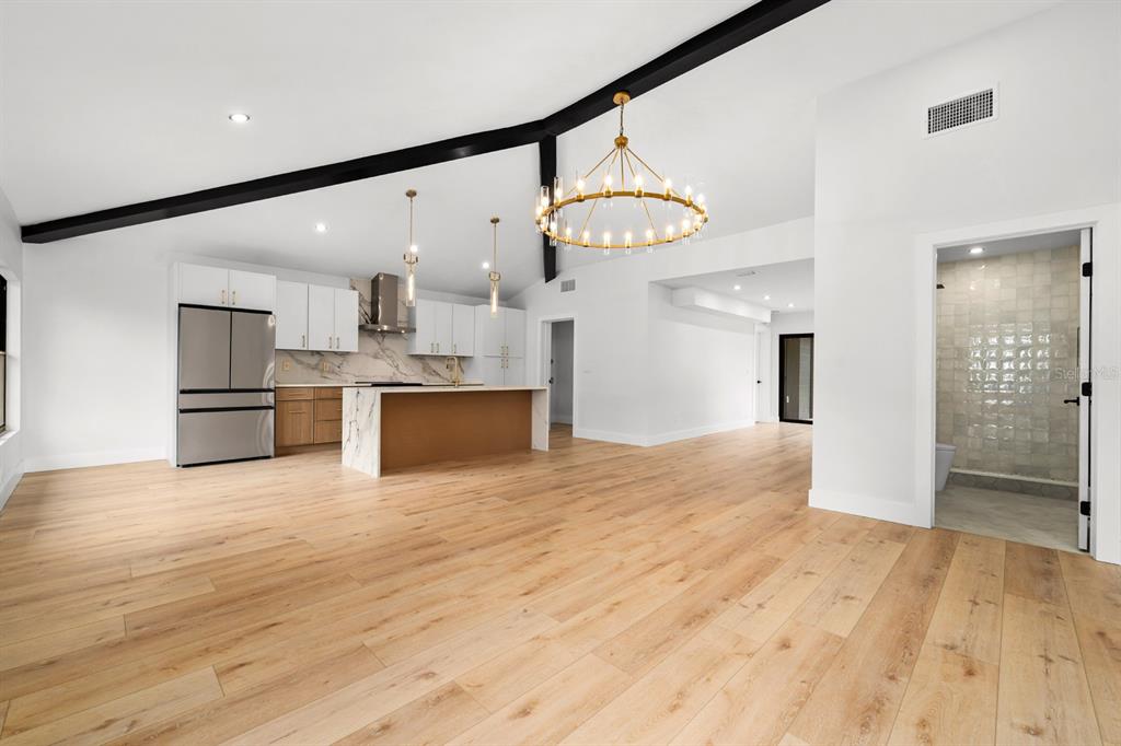 A modern open-concept kitchen and living area features light wood floors and a vaulted ceiling — 605 N WOODLYNNE AVENUE, TAMPA, FL