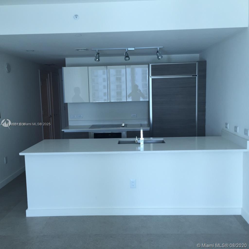 A modern kitchen features white cabinetry, a large island with a sink, and stainless appliances — 1100 S Miami Ave # 2911, Miami FL 33130, MIAMI, FL