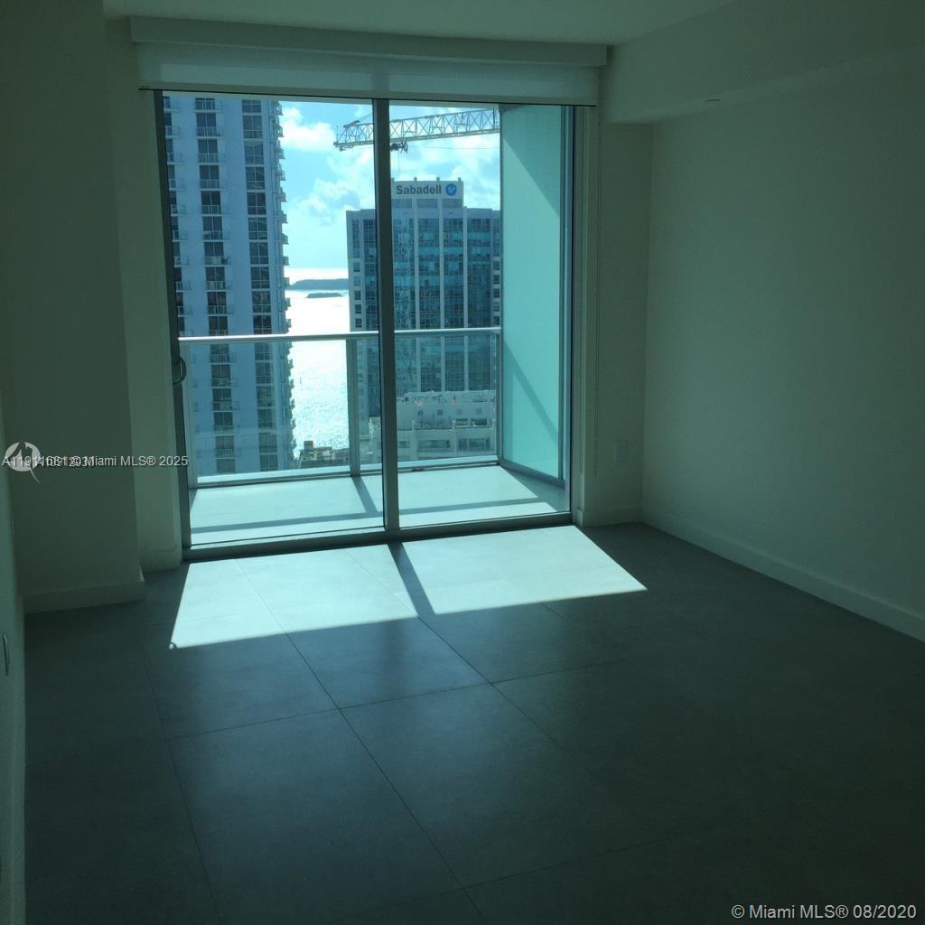 An empty room with large sliding glass doors leading to a balcony overlooking city buildings — 1100 S Miami Ave # 2911, Miami FL 33130, MIAMI, FL