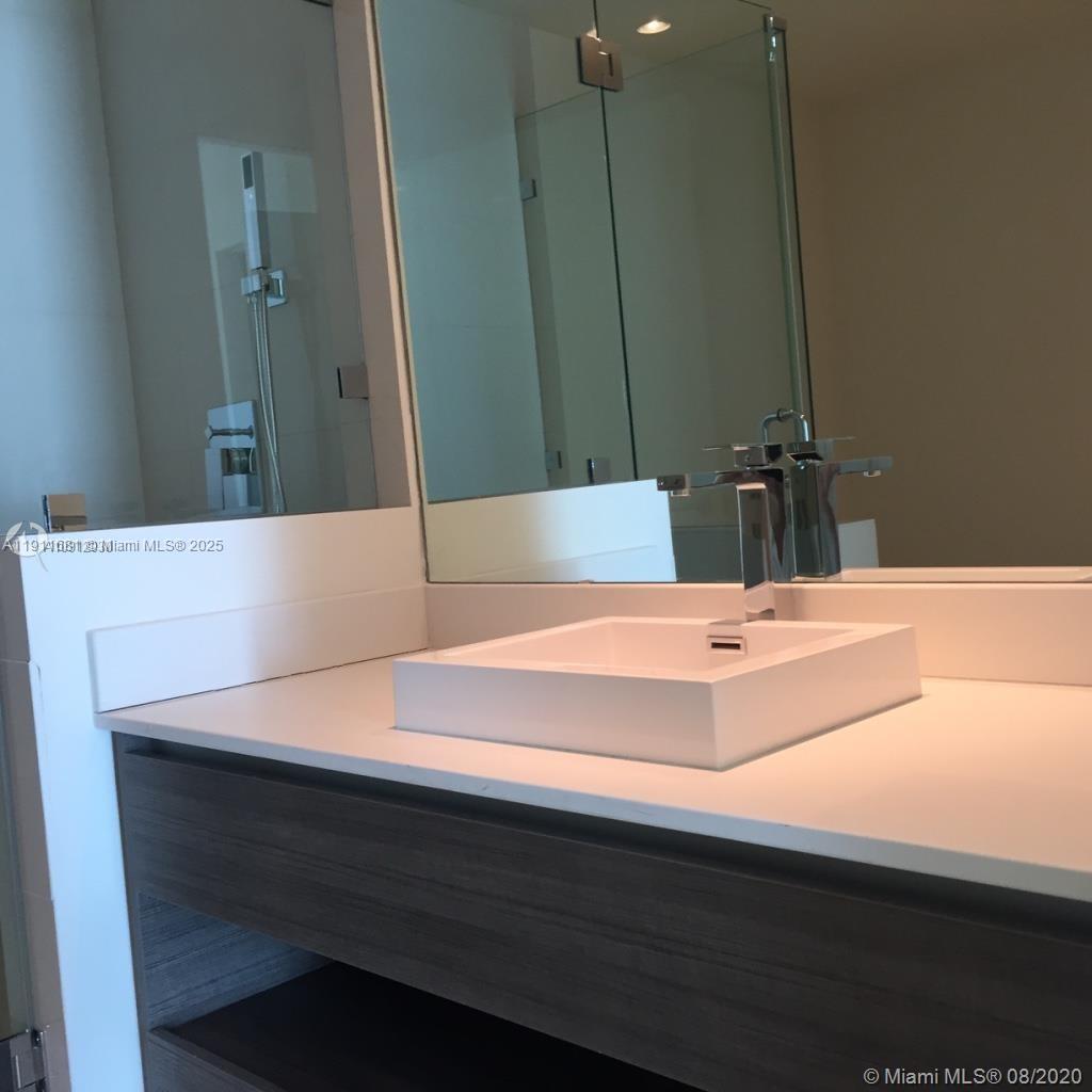 A modern bathroom features a white vessel sink on a dark wood vanity — 1100 S Miami Ave # 2911, Miami FL 33130, MIAMI, FL
