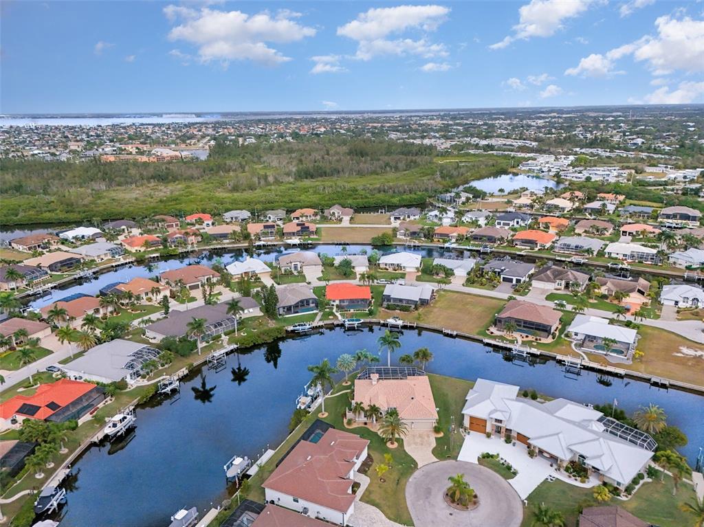 An aerial view shows waterfront houses with boat docks along a canal in a neighborhood — 1247 PINE SISKIN DRIVE, PUNTA GORDA, FL