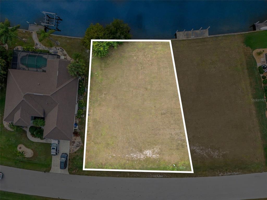 An aerial view shows a vacant, rectangular waterfront lot outlined in white — 1247 PINE SISKIN DRIVE, PUNTA GORDA, FL