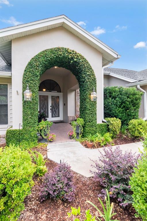 The exterior of a house features a vine-covered arched entryway and a landscaped front yard — 3306 WESTMORELAND DRIVE, TAMPA, FL