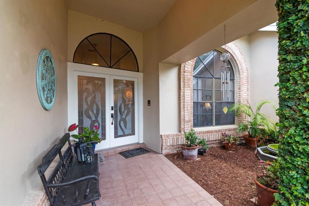 A covered entryway features a double glass door, a tiled floor, a bench, and landscaping — 3306 WESTMORELAND DRIVE, TAMPA, FL