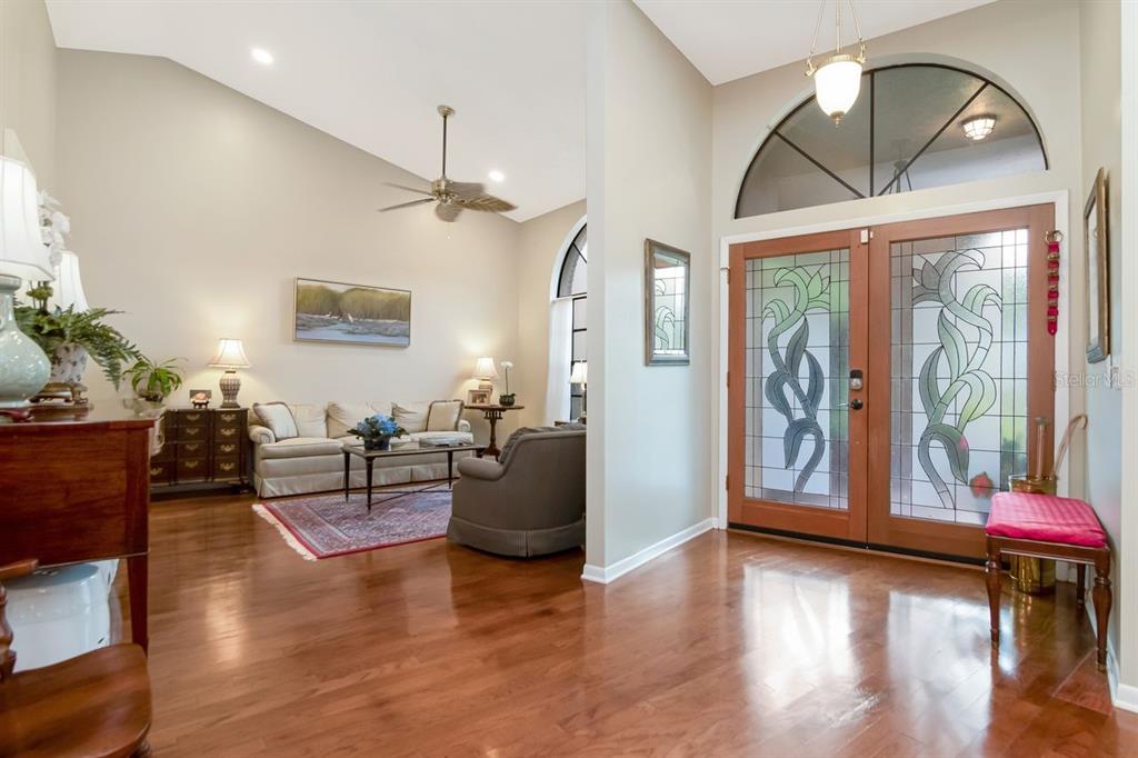 A bright entryway with hardwood floors leads into a living room with vaulted ceilings — 3306 WESTMORELAND DRIVE, TAMPA, FL