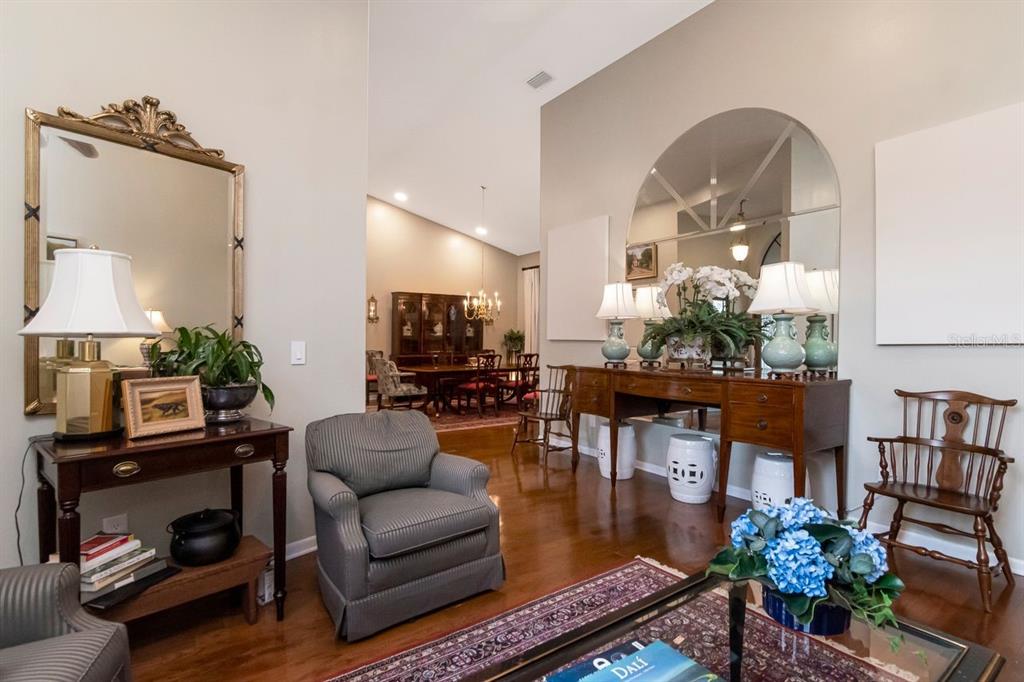A living room with hardwood floors, a large arched mirror, and a dining area beyond — 3306 WESTMORELAND DRIVE, TAMPA, FL