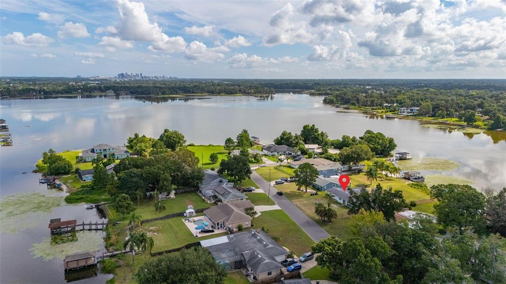 An aerial view shows a residential neighborhood situated along a large lake with a city skyline — 5701 PADGETT CIRCLE, ORLANDO, FL