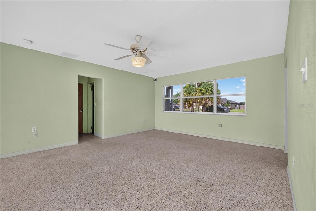 An empty room with light green walls, beige carpeting, a ceiling fan, and large windows — 5701 PADGETT CIRCLE, ORLANDO, FL