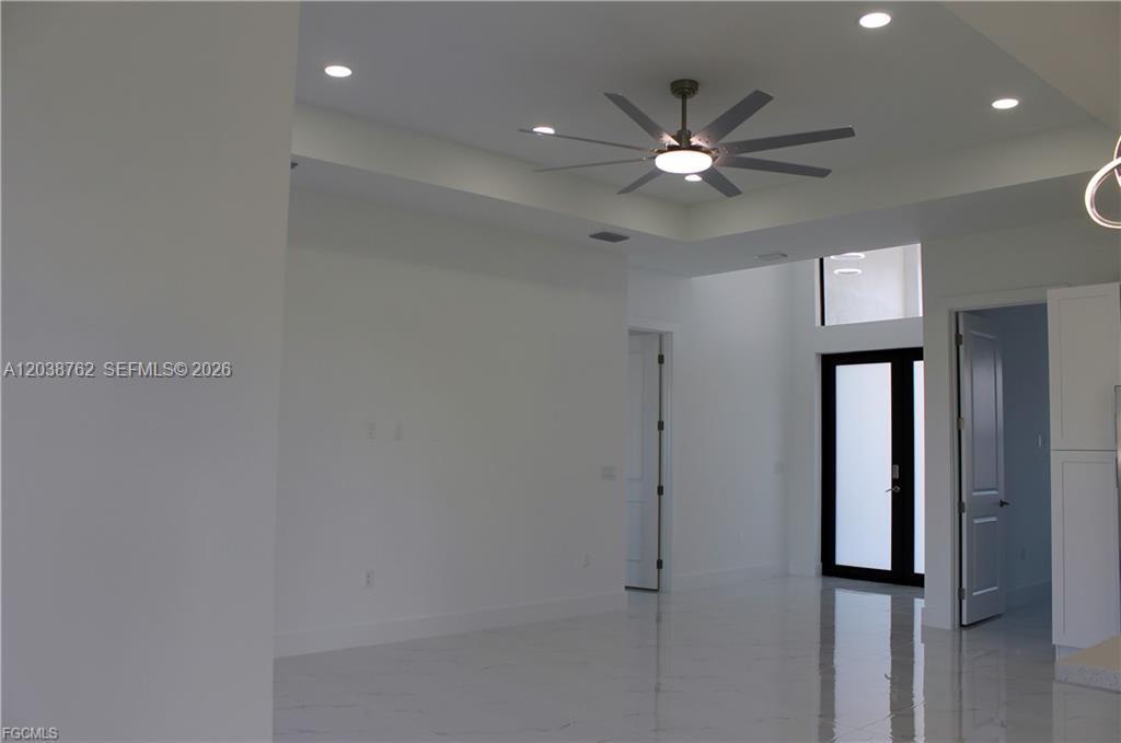 A modern living room features white walls, a tray ceiling with a fan, and tile flooring — 3316 7th St SW, Lehigh Acres FL 33976, LEHIGH ACRES, FL