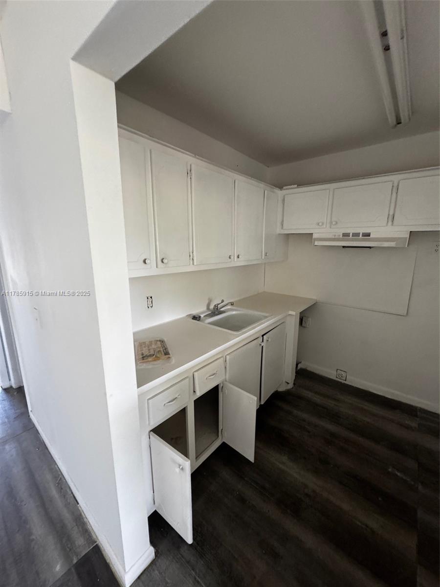 A small kitchen features white cabinets, a single-basin sink, and dark wood-look flooring — 42 Sheffield B # B, West Palm Beach FL 33417, WEST PALM BEACH, FL