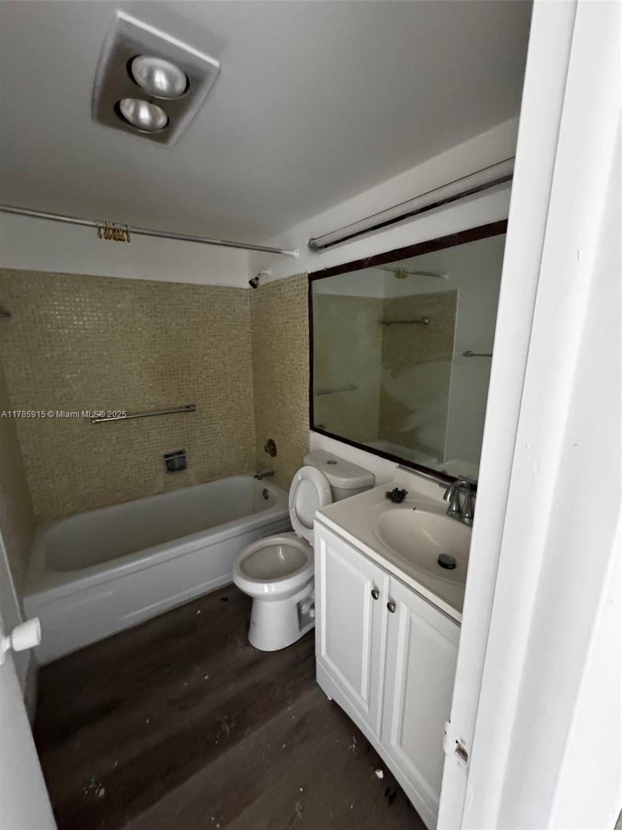 A bathroom features a white vanity, a toilet, a bathtub, and a large wall mirror — 42 Sheffield B # B, West Palm Beach FL 33417, WEST PALM BEACH, FL