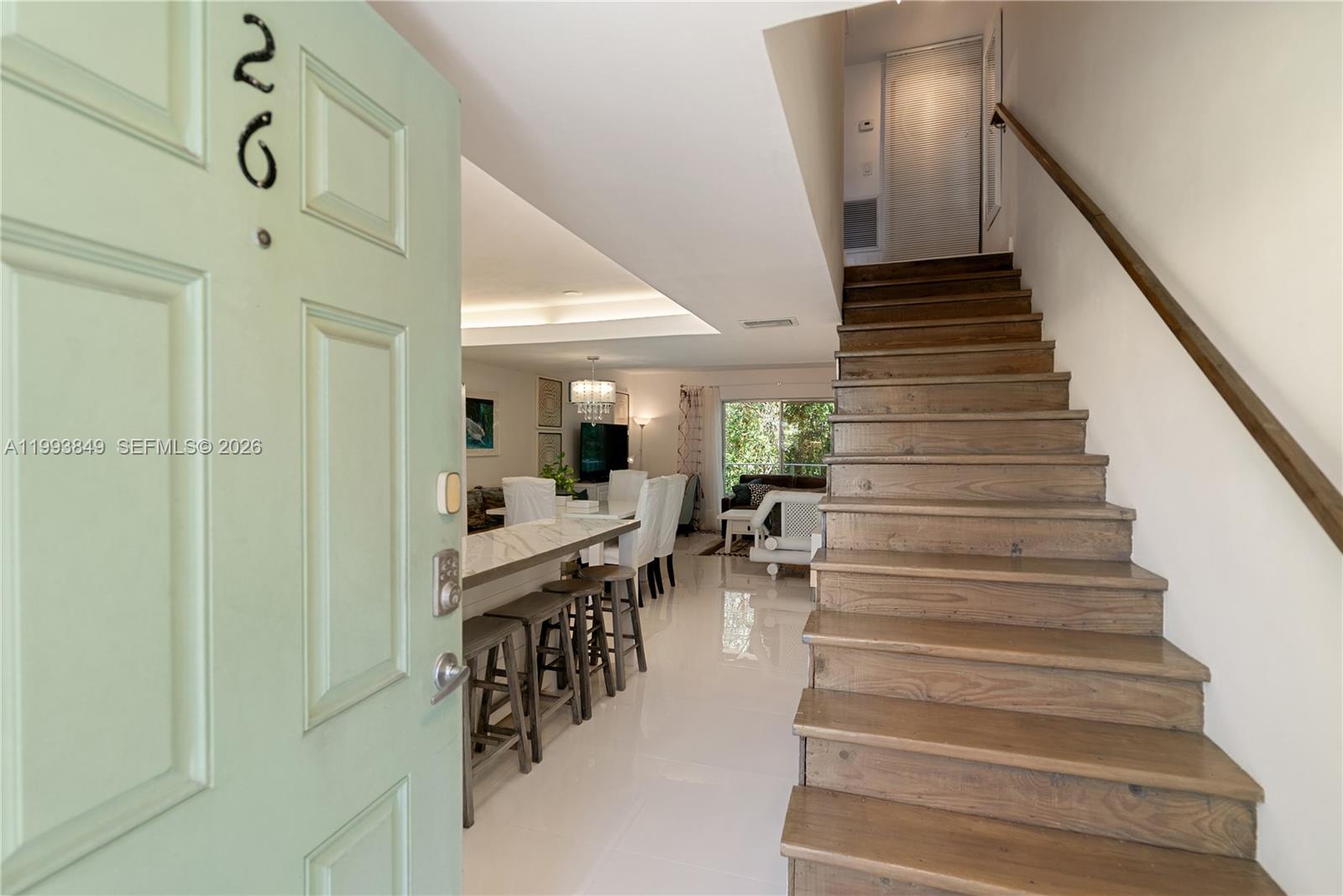 An open-concept living area features a kitchen island, dining space, and wooden staircase — 300 Ocean Dr # 26, Key Largo FL 33037, KEY LARGO, FL