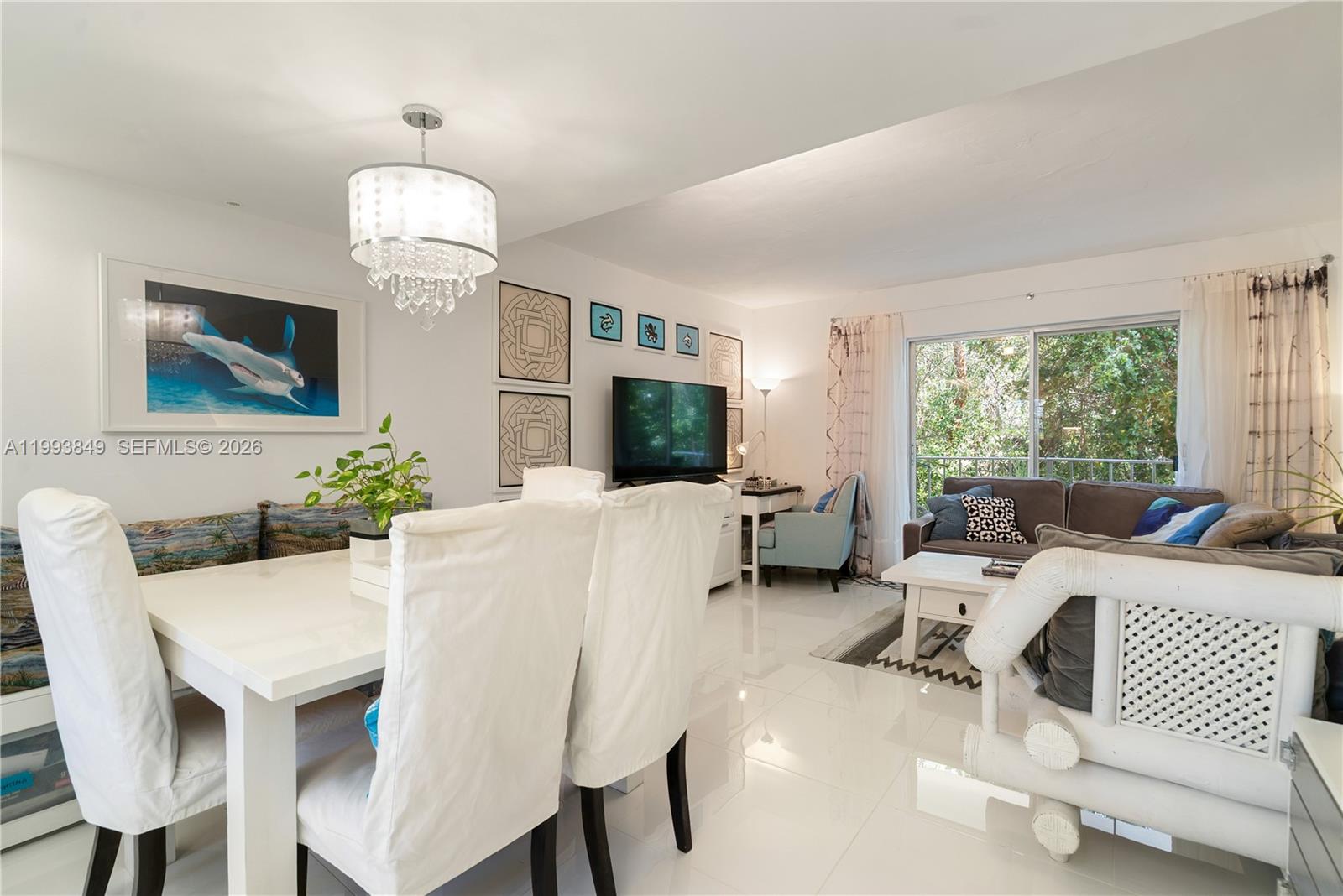 A dining area and living room feature white tile floors, a chandelier, and balcony access — 300 Ocean Dr # 26, Key Largo FL 33037, KEY LARGO, FL