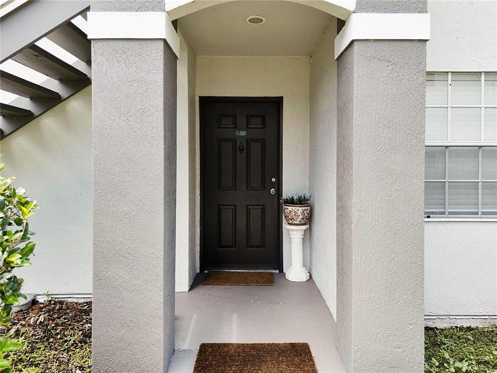 A dark brown front door is centered between two gray pillars under a covered entryway — 13929 FAIRWAY ISLAND DRIVE UNIT 818, ORLANDO, FL