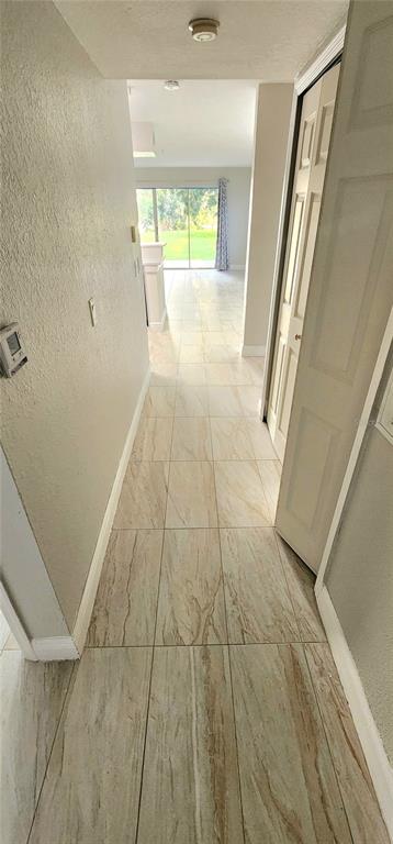 A kitchen with white cabinets, stainless steel appliances, and tile flooring overlooks a sliding glass door — 13929 FAIRWAY ISLAND DRIVE UNIT 818, ORLANDO, FL