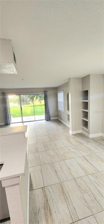 A kitchen features white cabinets, stainless steel appliances, and light-colored tile flooring — 13929 FAIRWAY ISLAND DRIVE UNIT 818, ORLANDO, FL