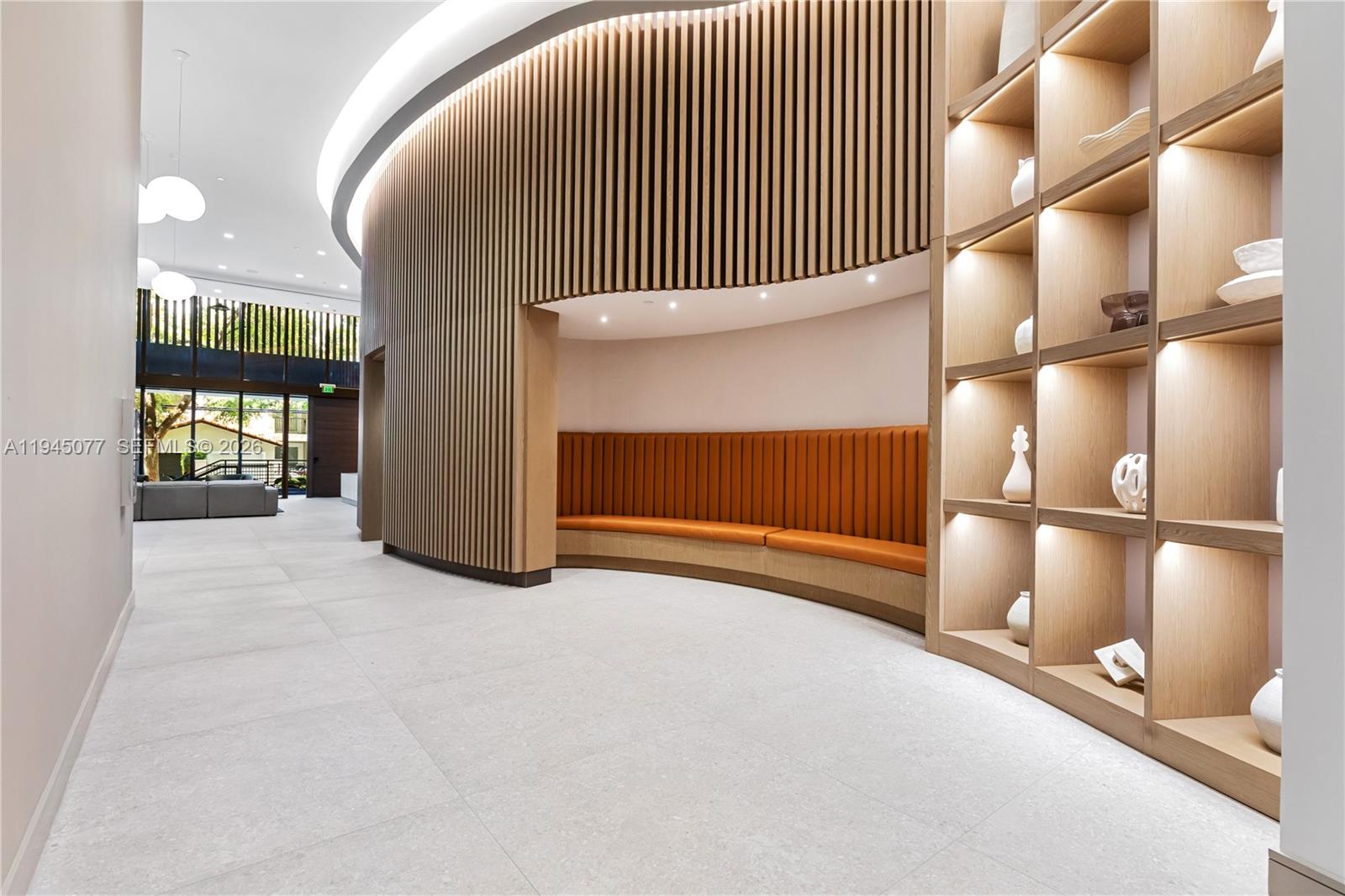 A modern lobby features a curved wood-slat wall, built-in orange bench seating, and illuminated shelving — 3034 Oak Avenue, Coconut Grove FL 33133, COCONUT GROVE, FL