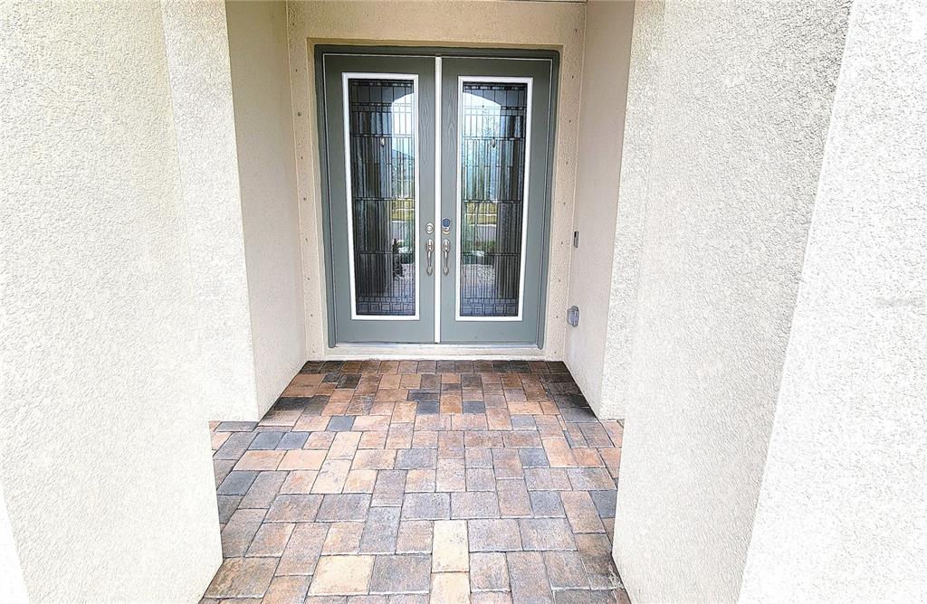 A front entryway features double glass-paneled doors and a multi-colored paver patio floor — 12854 BOGGY CREEK DRIVE, RIVERVIEW, FL
