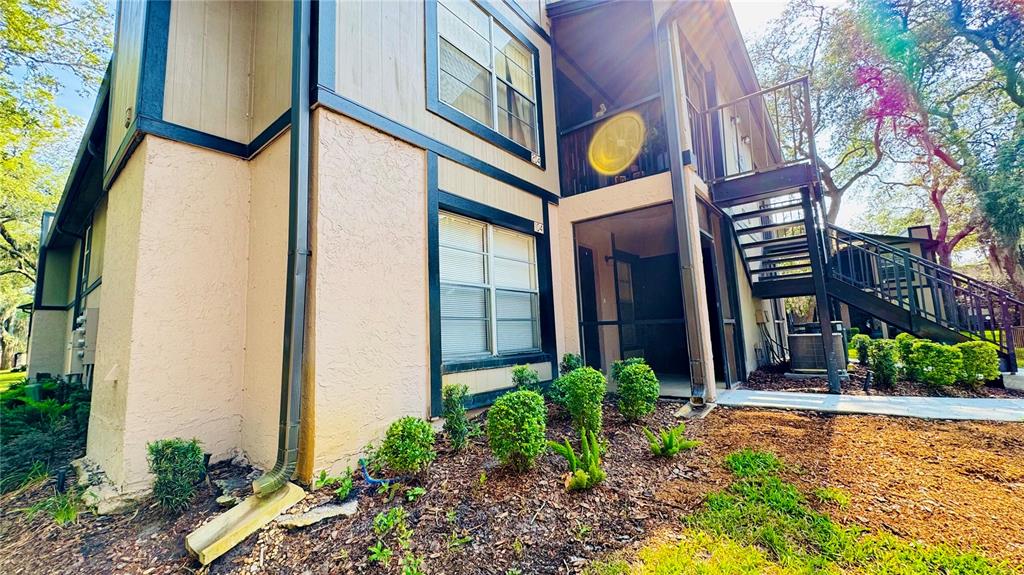 An exterior view of a two-story apartment building with a metal staircase and screened balconies — 4032 TUMBLE WOOD TRAIL UNIT 104, TAMPA, FL