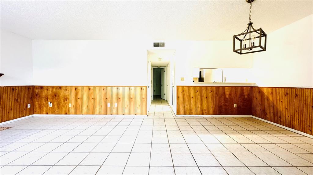 A dining area features white tile floors, wood wainscoting, and a geometric pendant light fixture — 4032 TUMBLE WOOD TRAIL UNIT 104, TAMPA, FL