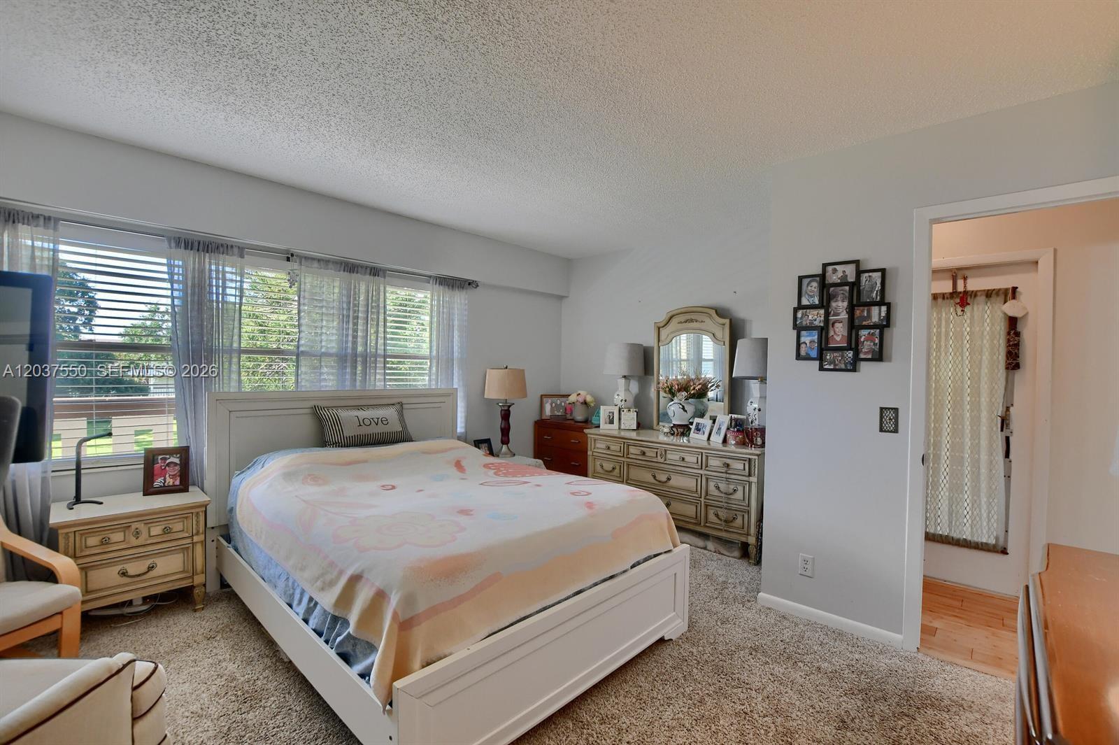 A bedroom features a white bed, a dresser with a mirror, and a doorway — 161 Mansfield D # 161, Boca Raton FL 33434, BOCA RATON, FL