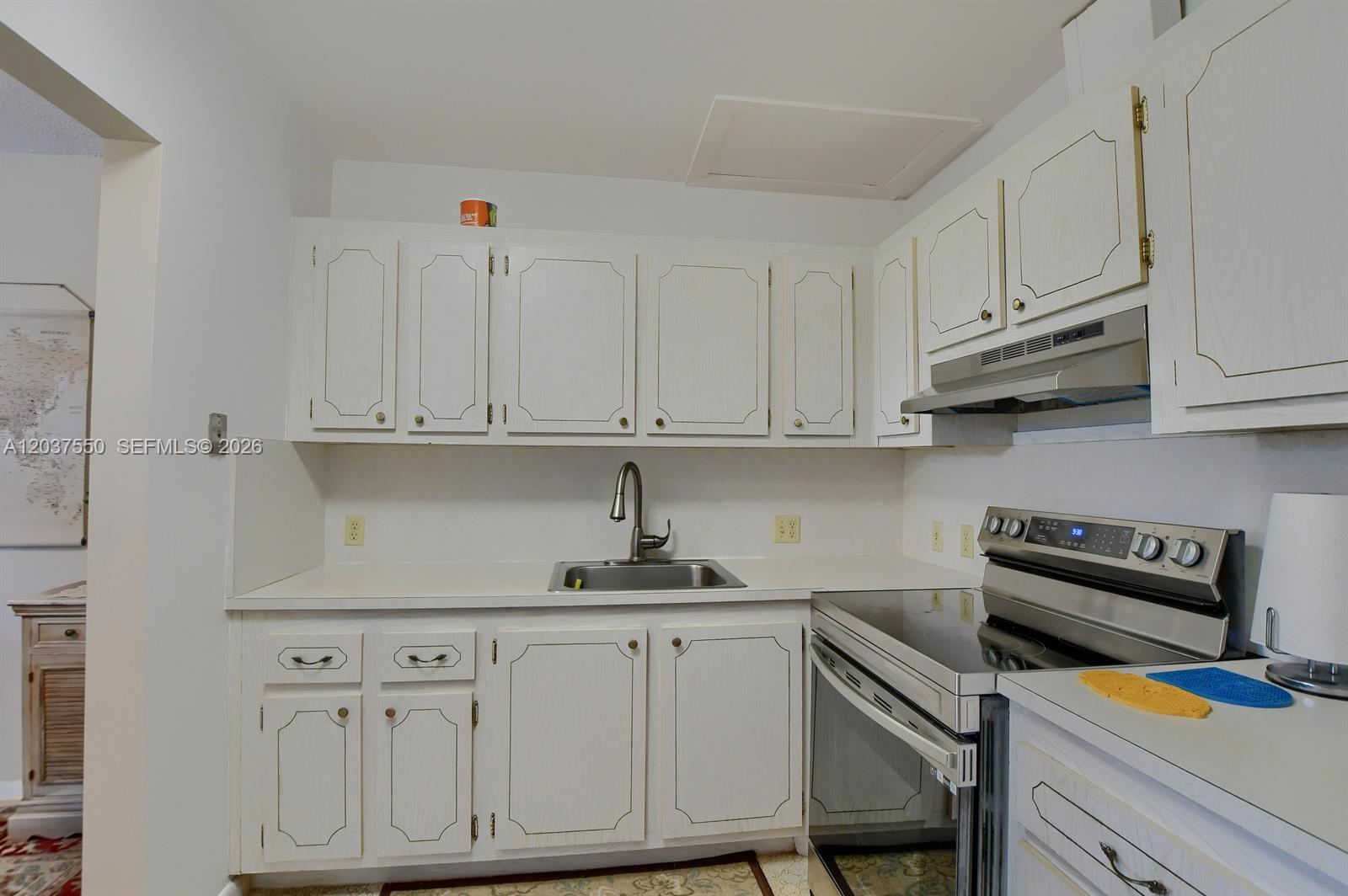A kitchen features white cabinets, a stainless steel sink, and a stainless steel electric range — 161 Mansfield D # 161, Boca Raton FL 33434, BOCA RATON, FL