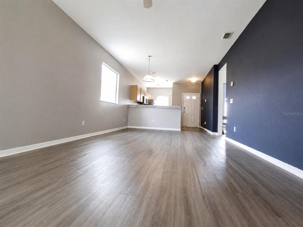 An open-concept living area features gray walls, a dark blue accent wall, and wood-look flooring — 15201 INDIAN CREEK DRIVE UNIT B, KISSIMMEE, FL