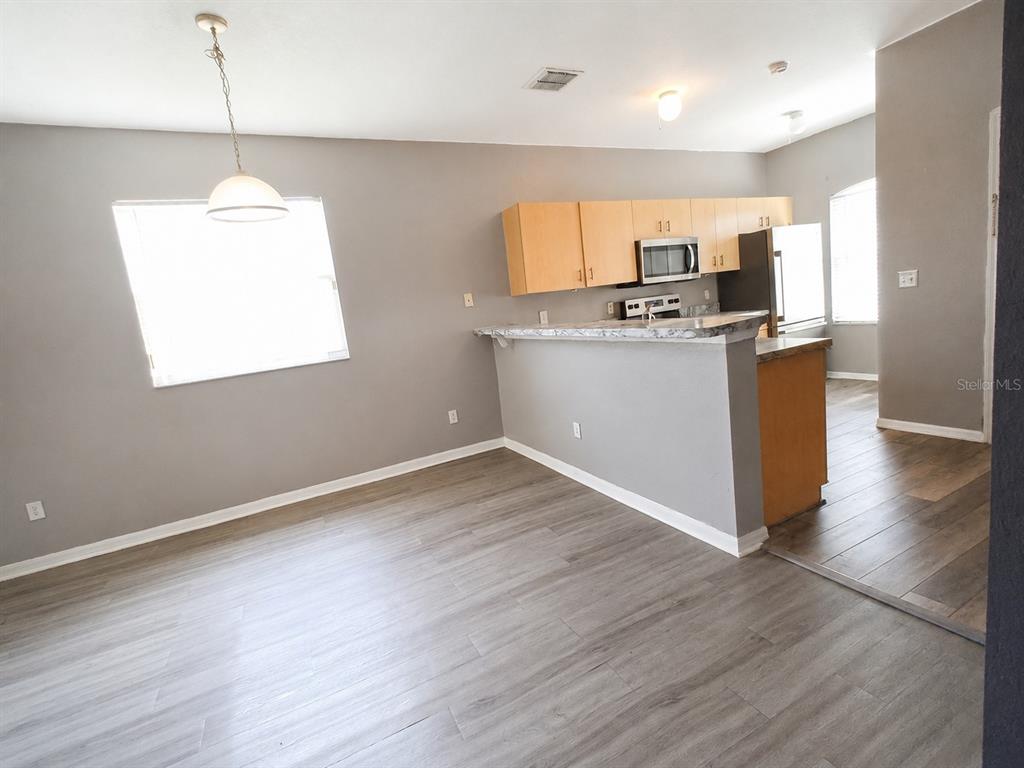 A kitchen with light wood cabinets and a breakfast bar overlooks a dining area — 15201 INDIAN CREEK DRIVE UNIT B, KISSIMMEE, FL
