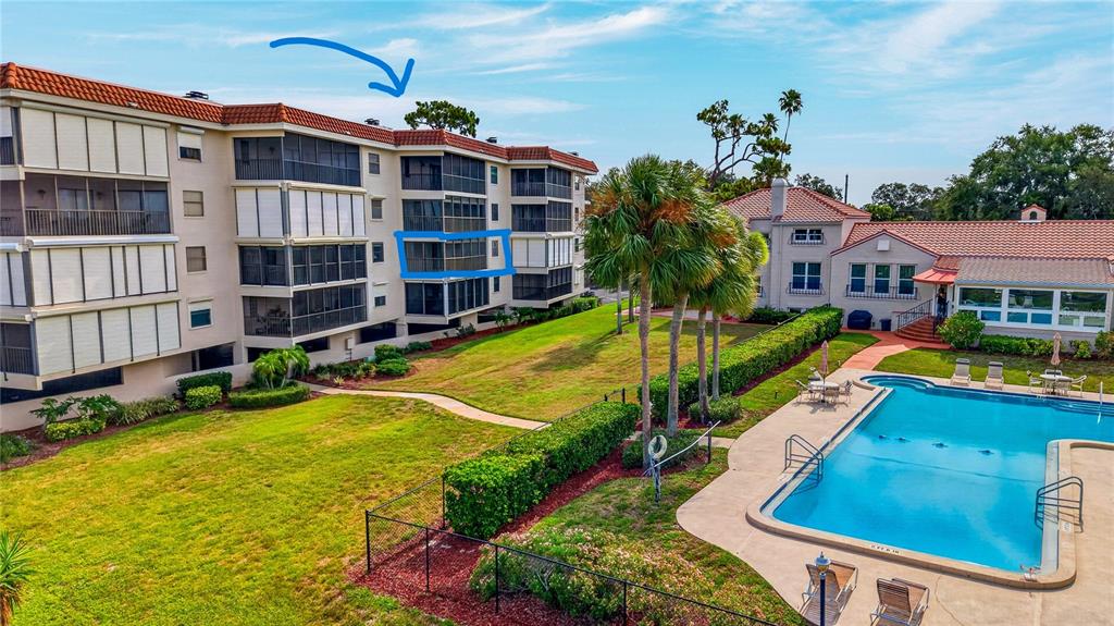 An exterior view of a multi-story apartment building with screened balconies next to a pool — 502 S FLORIDA AVENUE UNIT 124, TARPON SPRINGS, FL