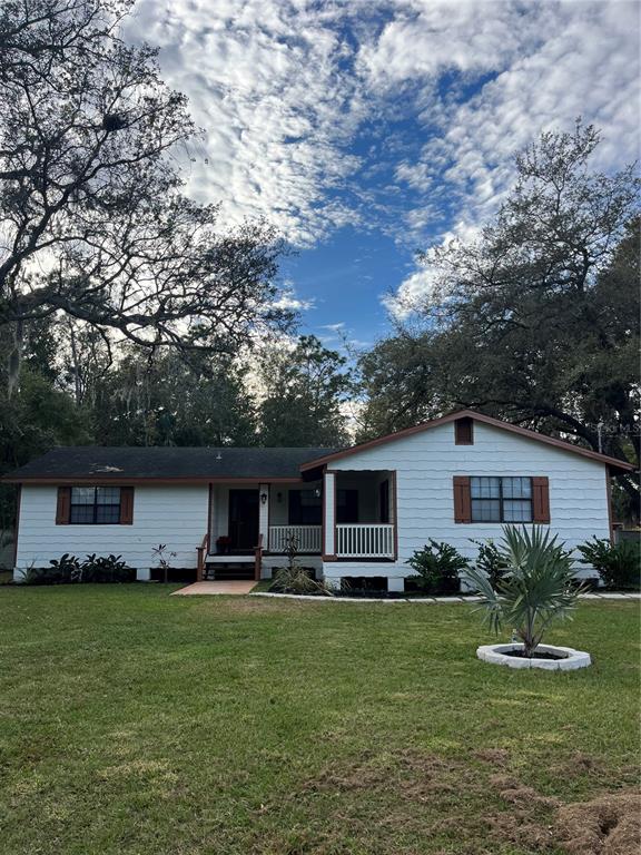 A white, single-story house with a front porch and brown shutters sits on a lawn — 512 STALLINGS AVENUE, DELTONA, FL