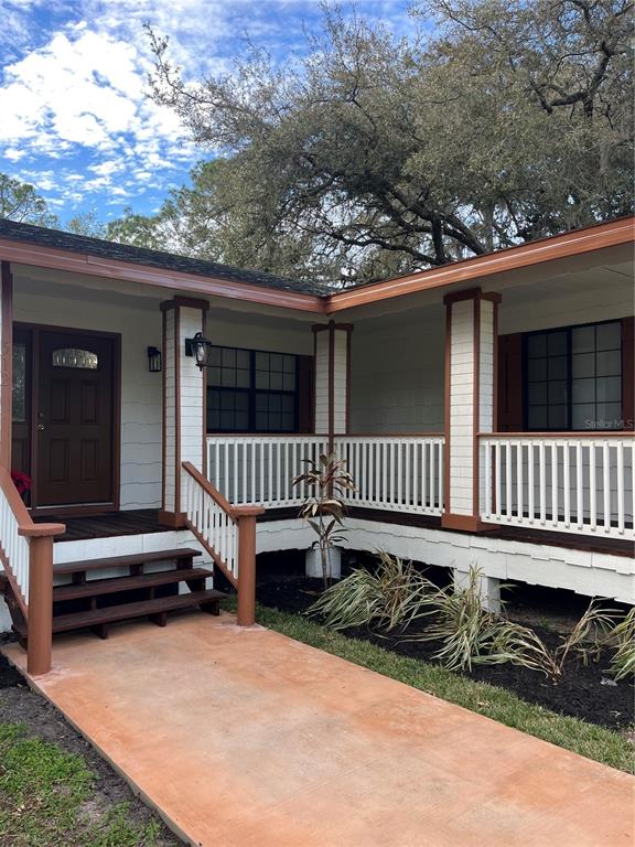 A house exterior features a covered porch with white railings, wooden steps, and dark trim — 512 STALLINGS AVENUE, DELTONA, FL
