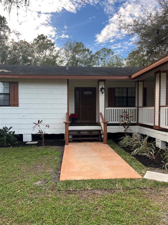 A white house with brown trim features a front porch and a concrete walkway — 512 STALLINGS AVENUE, DELTONA, FL