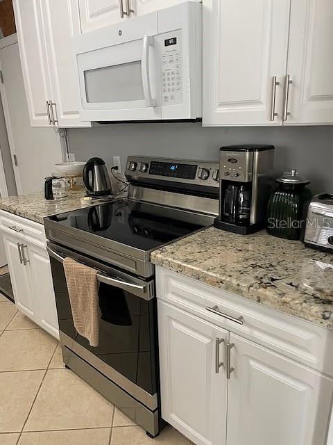A kitchen features white cabinets, a stainless steel stove, and granite countertops — 716 DOMINGUEZ DRIVE, LADY LAKE, FL