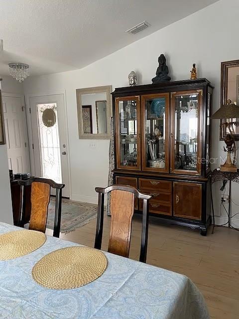 A dining room features a wooden hutch, a table with woven placemats, and a glass-paneled door — 716 DOMINGUEZ DRIVE, LADY LAKE, FL