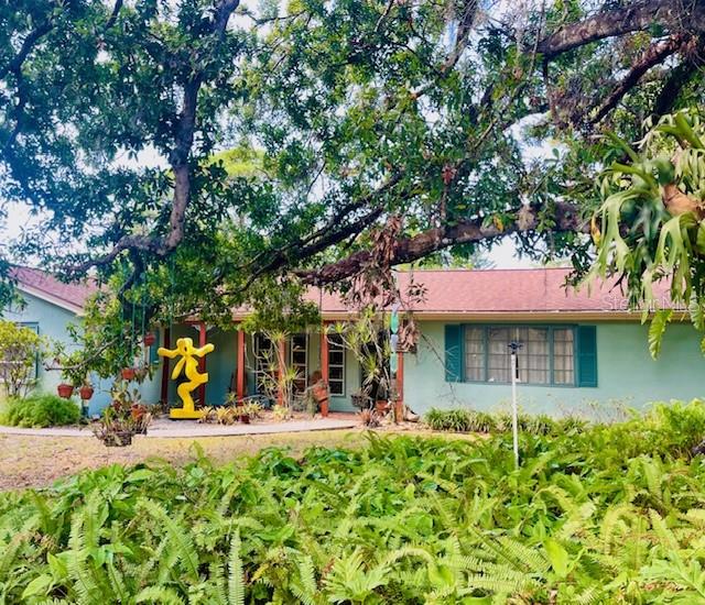 A light green house with a red roof is partially obscured by a large oak tree — 550 46TH STREET, SARASOTA, FL