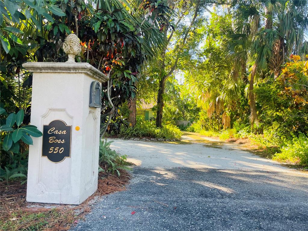 A white masonry pillar with a pineapple finial stands at the entrance of a driveway — 550 46TH STREET, SARASOTA, FL