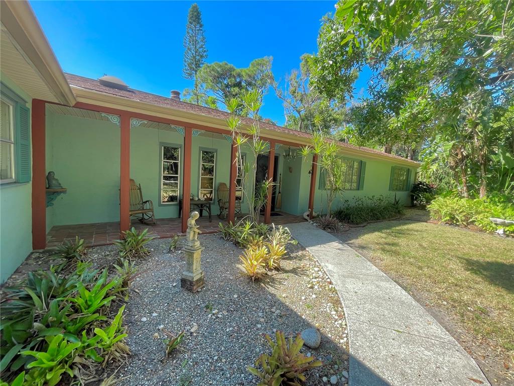 A light green house with a covered front porch, brick flooring, and a gravel garden — 550 46TH STREET, SARASOTA, FL