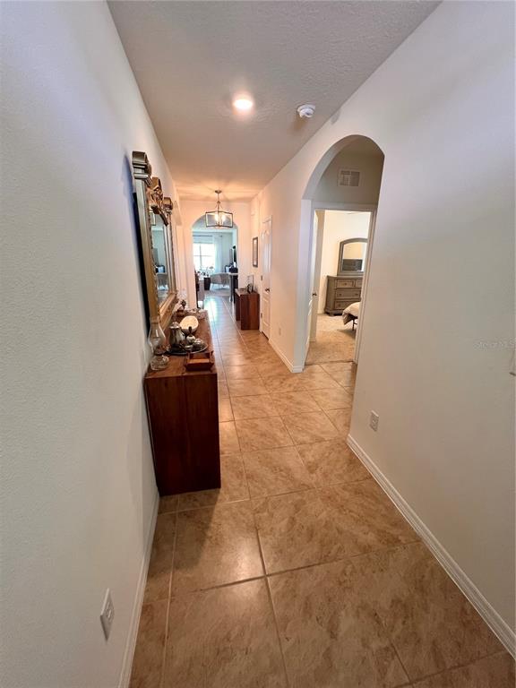A tiled hallway leads to an arched doorway revealing a bedroom with a dresser — 1267 IGUANA LOOP, DAVENPORT, FL