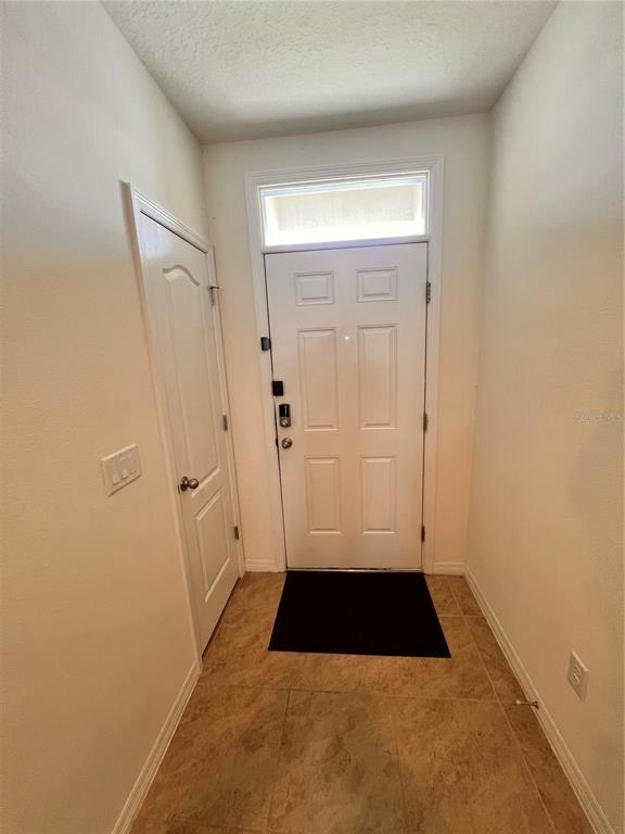 An entryway features a white front door with a transom window and tile flooring — 1267 IGUANA LOOP, DAVENPORT, FL