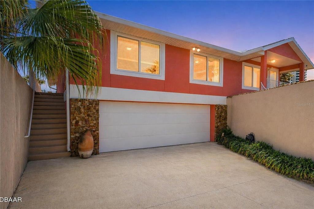 A two-story house with a white garage door, stone accents, and an exterior staircase — 1504 N ATLANTIC AVENUE, DAYTONA BEACH, FL