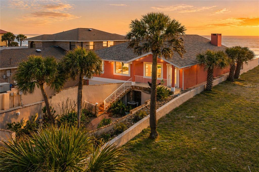 An elevated view of a coastal home with a sunken garden and palm trees at sunset — 1504 N ATLANTIC AVENUE, DAYTONA BEACH, FL