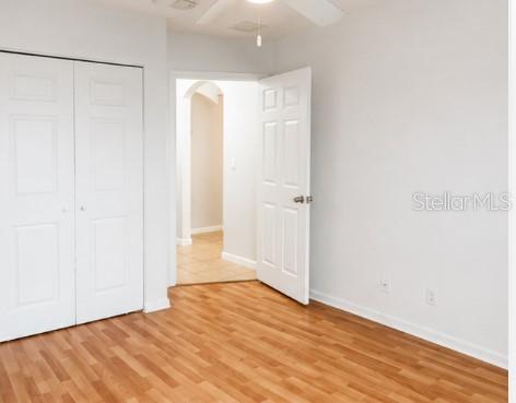 An empty room features light wood-look flooring, white walls, a closet, and an open doorway — 2928 HIDDEN HILLS ROAD UNIT 1405, WEST PALM BEACH, FL
