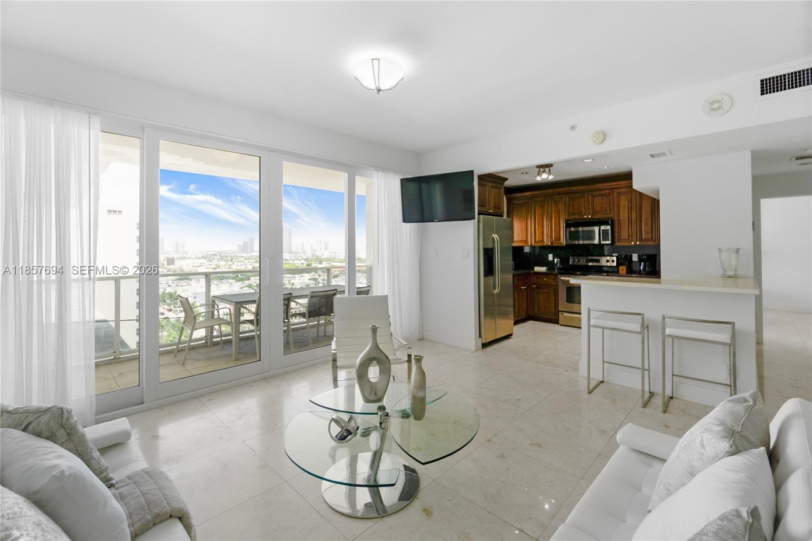 A living room with tile floors, a glass coffee table, and an adjacent open kitchen — 100 Lincoln Rd, Miami Beach FL 33139, MIAMI BEACH, FL