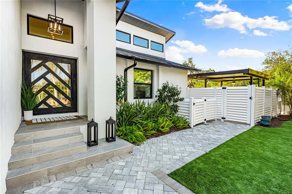 A modern home exterior features a geometric front door, tiled steps, and a paved walkway — 2500 MONTEREY STREET, SARASOTA, FL