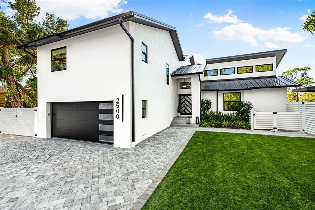 A modern white house with a black garage door, metal roof, and paved driveway — 2500 MONTEREY STREET, SARASOTA, FL
