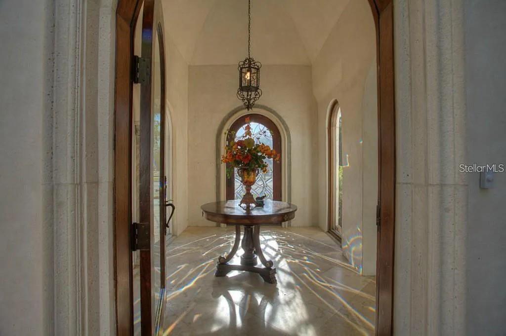 A foyer features a round wooden table, a hanging lantern, and arched doorways — 100 W DAVIS BOULEVARD, TAMPA, FL
