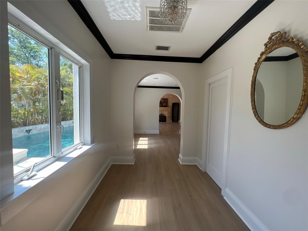 A hallway with light wood floors, arched doorways, black crown molding, and a pool view — 100 W DAVIS BOULEVARD, TAMPA, FL