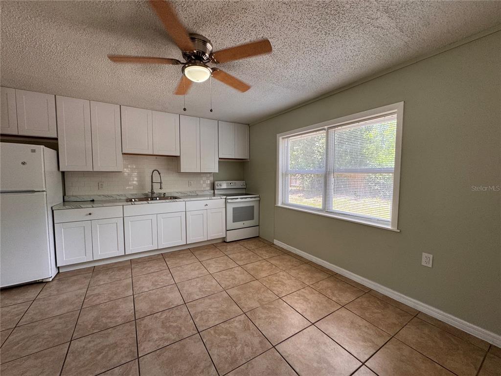 A tiled living area features a stained-glass door, white kitchen cabinets, and a staircase — 538 ORANGE STREET UNIT 538, MASCOTTE, FL
