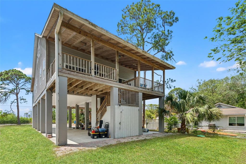 A two-story house elevated on concrete pilings with a wooden deck and staircase — 1566 INDIAN BAY ROAD, SPRING HILL, FL