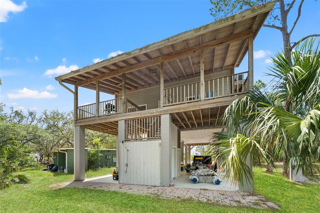 An elevated two-story house with a wooden deck, outdoor shower, and covered ground-level parking — 1566 INDIAN BAY ROAD, SPRING HILL, FL
